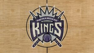 Center-court Sacramento Kings logo painted on a wooden basketball court surface.