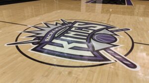 Basketball court floor featuring the Sacramento Kings center logo in purple, black, and white.