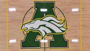 Gym hardwood floor featuring a large green and yellow athletic logo with a bulldog head centered over a bold A letter outline (courtside emblem).