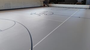 Indoor gym floor with a large 'Jets' logo at center and white and dark blue court lines.